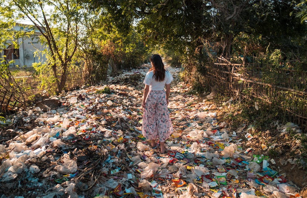 Vrouw staand op een enorme berg afval